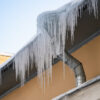 Frozen ice from gutters needing maintenance to protect roof in the winter.