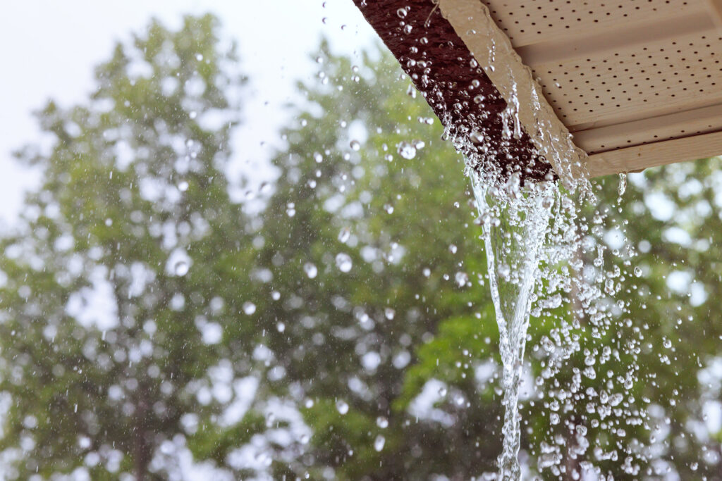 During heavy rain, water comes from over gutters requiring spring gutter maintenance.